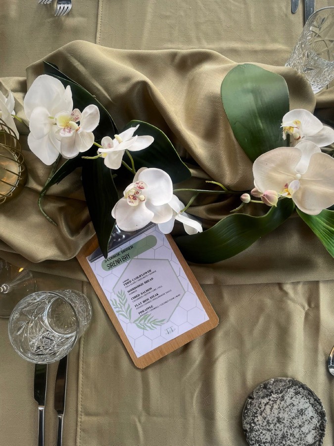 Table decorated with white orchids and a printed menu