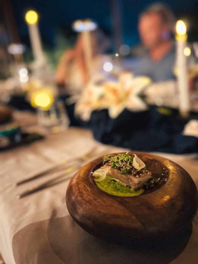 Plated course in a wooden bowl at a candlelit dinner table