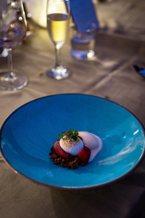 Plated dessert in a blue bowl next to a glass of champagne