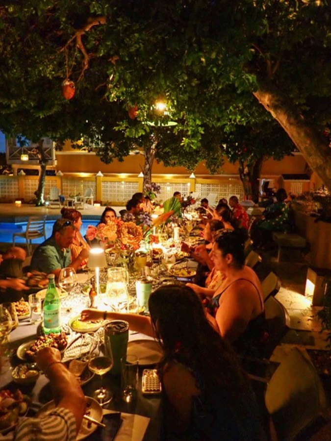 Guests at a long candlelit table by the pool in the evening